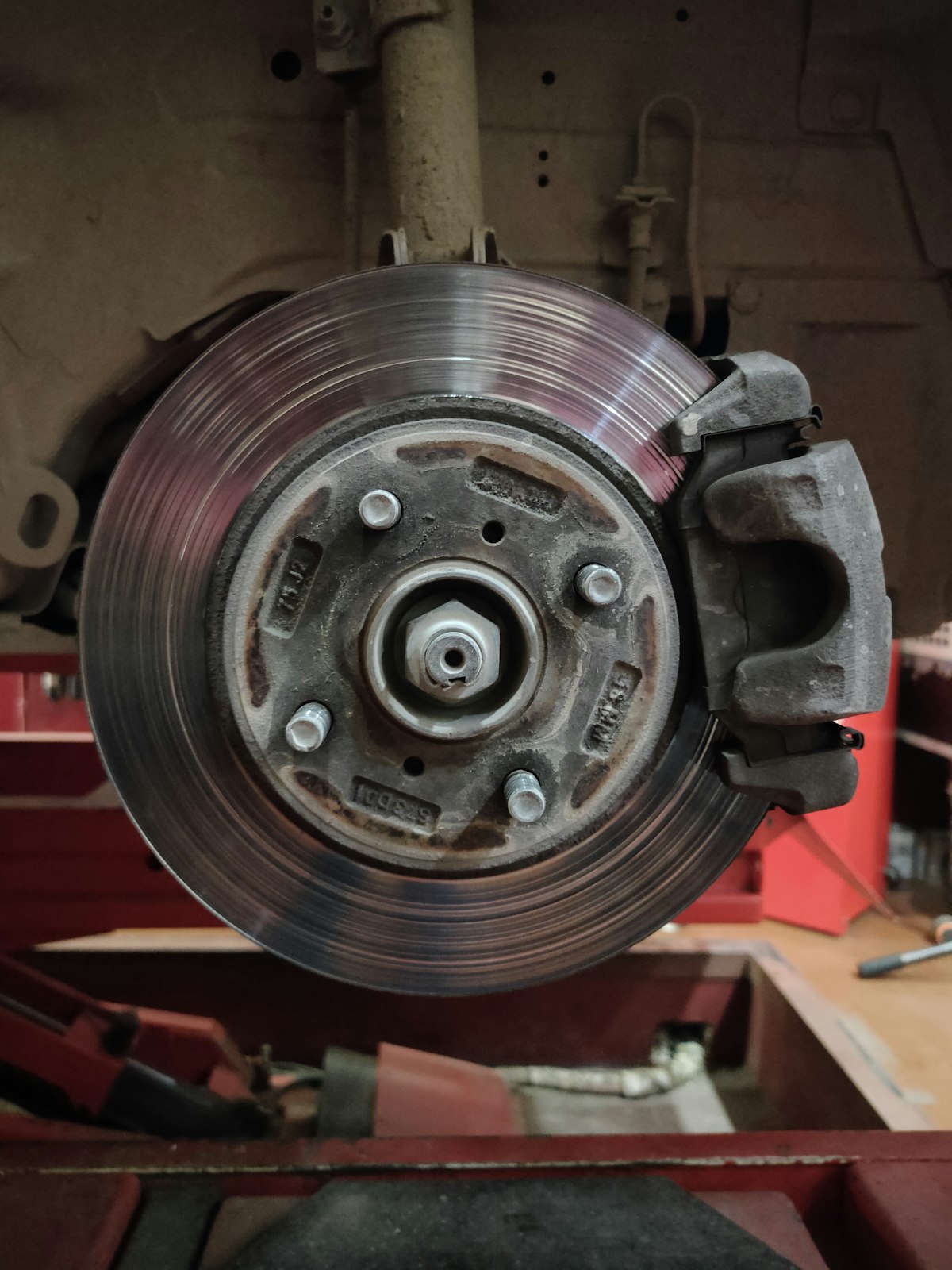 Close-up of a car brake rotor and caliper on a mobile mechanic's jack stand