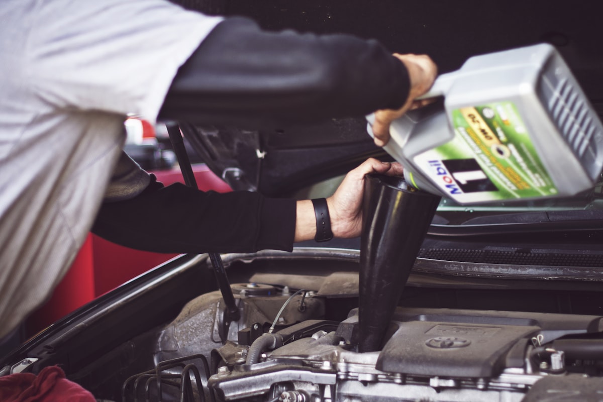 Mechanic pouring fresh oil into a car engine during a mobile maintenance visit