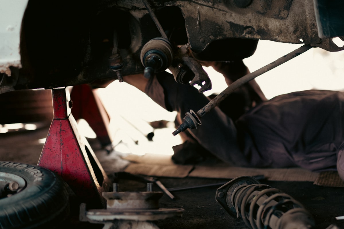 Mechanic working underneath a car on a jack stand, repairing the suspension